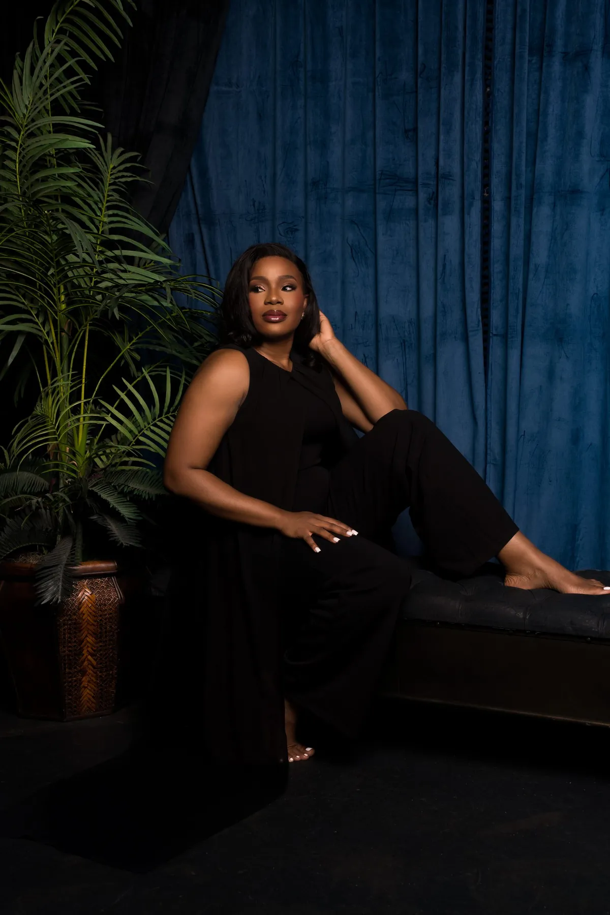 Studio portrait in a black outfit against blue curtains